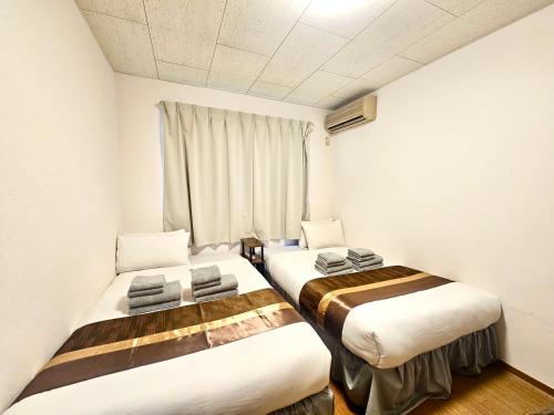 two beds in a small room with a window at Fuji Flat 新大久保駅から徒歩20秒 新宿駅も徒歩15分 有名レストラン多数 歌舞伎町も歩いて行けます in Tokyo