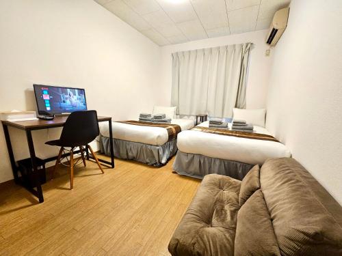 a hotel room with two beds and a desk at Fuji Flat 新大久保駅から徒歩20秒 新宿駅も徒歩15分 有名レストラン多数 歌舞伎町も歩いて行けます in Tokyo
