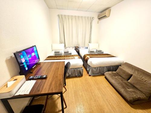 a hotel room with two beds and a table and a couch at Fuji Flat 新大久保駅から徒歩20秒 新宿駅も徒歩15分 有名レストラン多数 歌舞伎町も歩いて行けます in Tokyo
