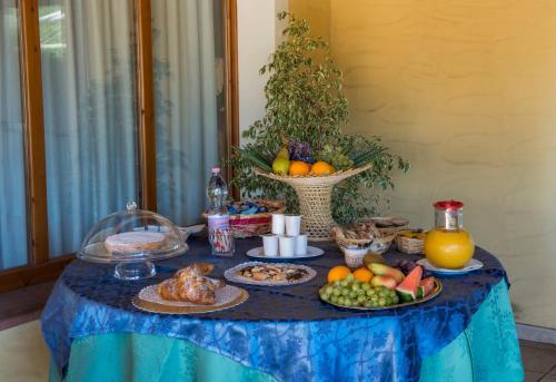 a blue table topped with plates of food and fruit at Hotel Perda Rubia in San Giovanni Suèrgiu
