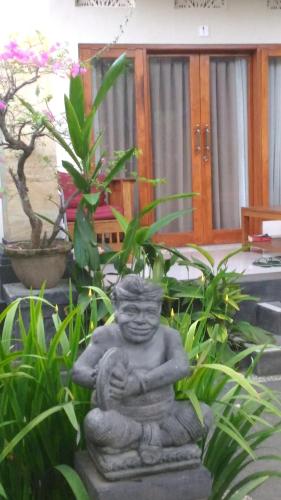 a statue of a man sitting in front of plants at Suryadina Guest House in Ubud