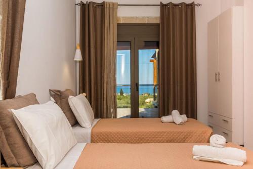 two beds in a room with a view of the ocean at Villa Elea with Private Pool in Zakynthos