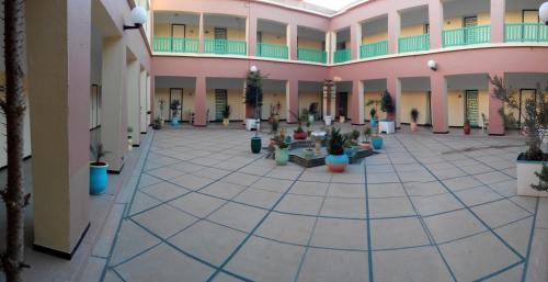 an empty hallway with potted plants in a building at Hotel Les Amandiers in Tafraoute