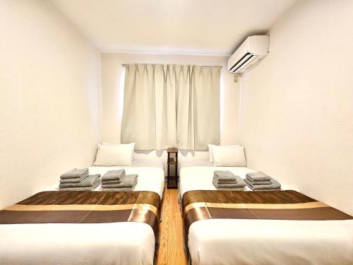 two beds in a small room with a window at Fuji Flat 新大久保駅から徒歩20秒 新宿駅も徒歩15分 有名レストラン多数 歌舞伎町も歩いて行けます in Tokyo