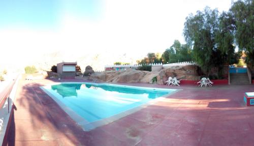 a swimming pool in a backyard with a rock wall at Hotel Les Amandiers in Tafraoute