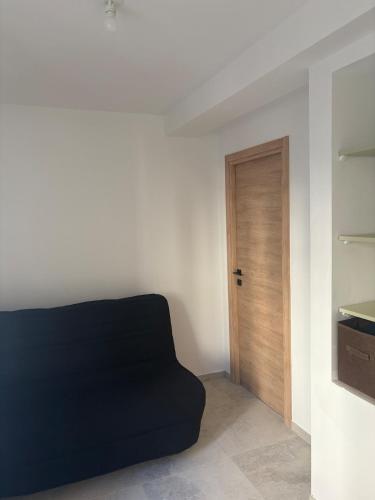 a room with a black couch and a wooden door at Appartement La Colle sur Loup in La Colle-sur-Loup