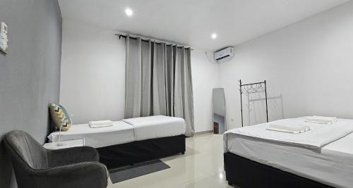 a room with two beds and a chair in it at Bilene Harmony Home in Vila Praia Do Bilene