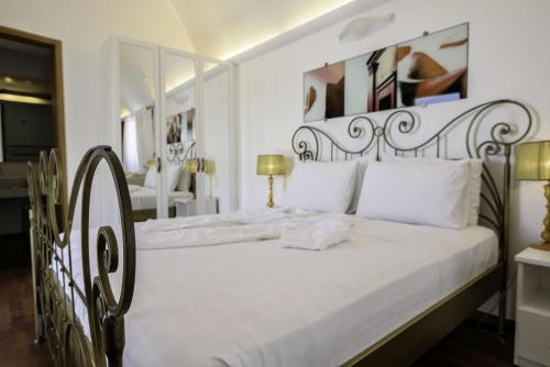 1 dormitorio con cama blanca y cabecero de hierro forjado en La Mer Deluxe Hotel & Spa, en Kamari