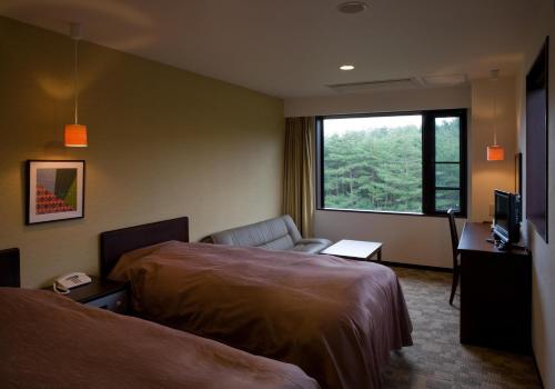 a hotel room with two beds and a window at Jiragonno Fuji no Yakata in Narusawa