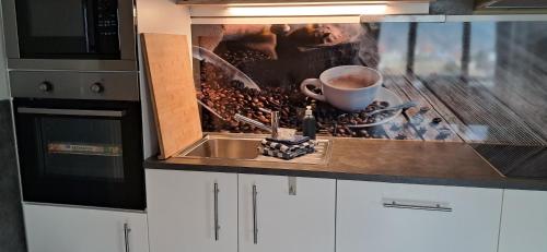 a kitchen with a sink and a cup of coffee at Apartmenthaus Hinterer in Bad Goisern