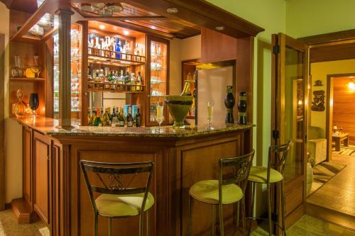 a bar with two chairs and a counter with drinks at Hotel Azaleia in Gramado