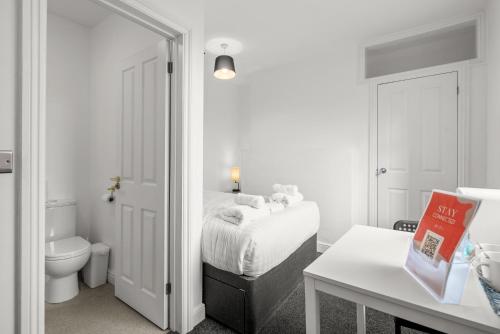 a white bedroom with a bed and a toilet at 6 BR 4 Bath Central Worcester Sleeps 12 in Worcester