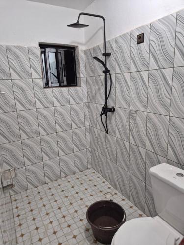 a bathroom with a shower with a toilet and a bucket at G and E Guesthouse in Kumba