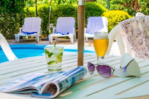 a table with a book and sunglasses and a glass of beer at Hotel Azaleia in Gramado