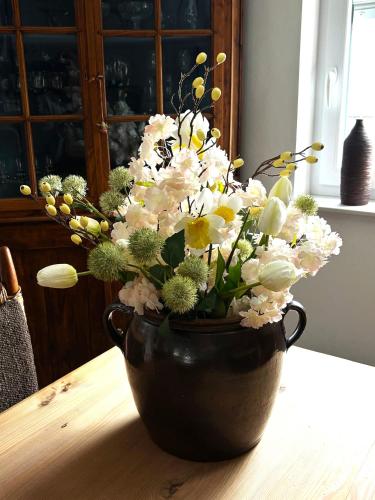 a black vase filled with flowers on a table at Ferienwohnung HeilbadOase in Erwitte