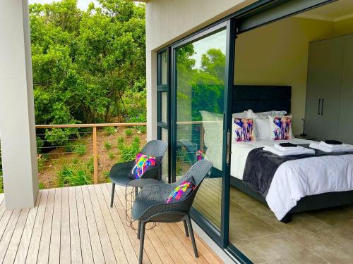 a bedroom with a bed and two chairs on a balcony at Number 1 at SuPaViews in Wilderness