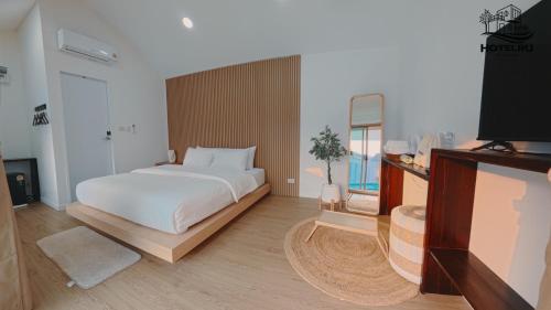 a bedroom with a large white bed and a flat screen tv at Hotelru Koh Larn-โฮเต็ลรุ เกาะล้าน in Ko Lan