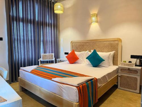 a bedroom with a large bed with colorful pillows at Hotel Catamaran Bay by Ayur Ayur in Negombo