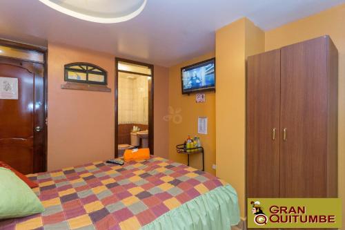 a bedroom with a bed and a cabinet and a bathroom at Hotel Gran Quitumbe in Quito