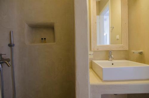 a bathroom with a sink and a mirror and a shower at Yialos Ios Hotel in Ios Chora