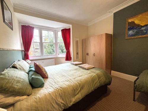 a bedroom with a large bed with red curtains at Silverdale Holiday Apartments in Eastbourne