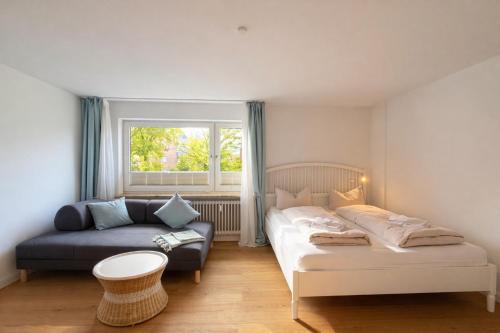 a bedroom with a bed and a couch and a window at Beachfront Studio - 1 Strandreihe in Scharbeutz