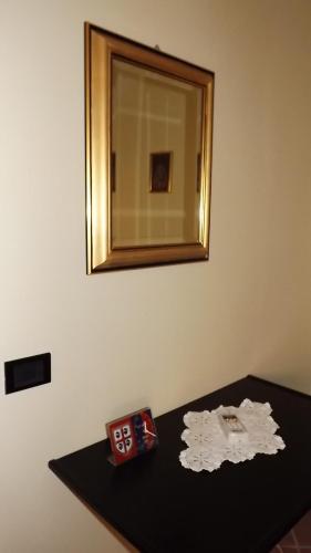 B&B I Tre Nuraghi في ماكومير: مرآة على جدار فوق طاولة سوداء مع مرآة