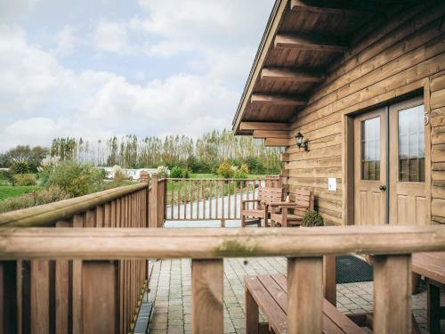 a porch of a wooden cabin with a wooden bench at Lake View Lodges - 25076 in Old Leake