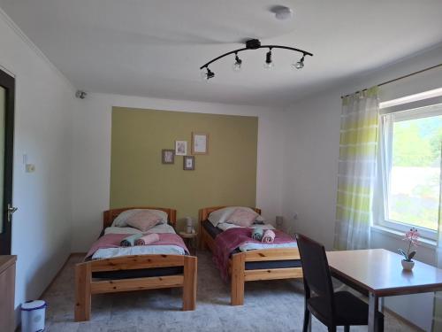two beds in a room with a table and a dining room at Szemben apartment in Csengőd