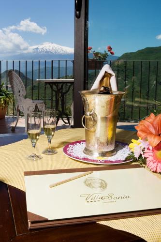 a table with wine glasses and a bucket with a bottle at Hotel Villa Sonia in Taormina