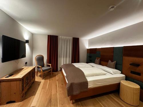 a hotel room with a bed and a television at Ciasa Milandura NEW SUMMER 2025 in San Cassiano