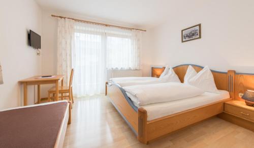 a bedroom with a bed and a table and a desk at Apartpension Oberhauser in Kaprun
