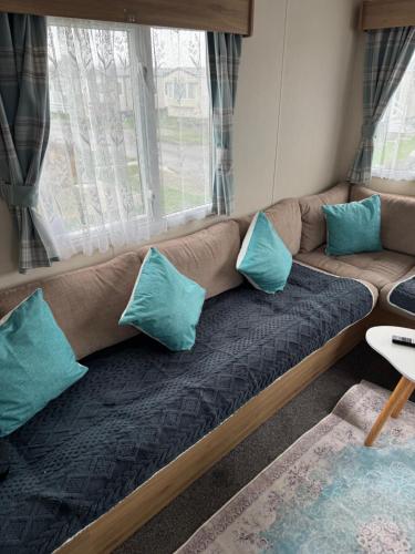 a couch with blue pillows in a living room at Dawbers Retreat in Selsey