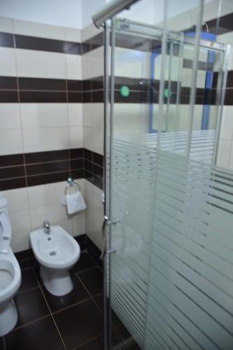 a bathroom with a toilet and a glass shower stall at Royal gaz Hotel in Durrës