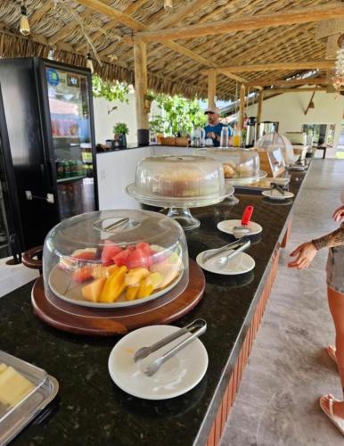a buffet line with a tray of fruit on a counter at Pousada Casa Caju Bangalows in Cumbuco