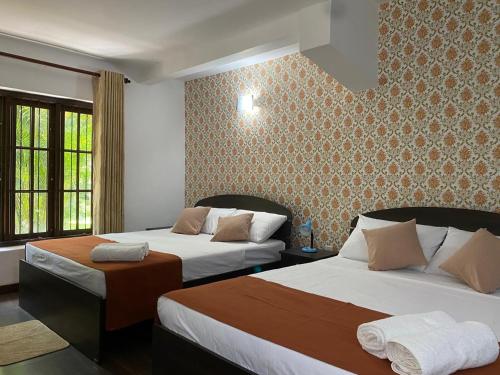 a hotel room with two beds and a window at Kudaarala Heritage in Kengalla