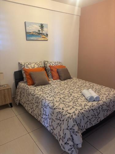 a bedroom with a bed with orange and gray pillows at Kaz Toutoune in Saint-Leu