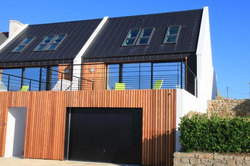 une maison avec un garage noir et une clôture dans l'établissement Villa de la plage de Plouescat, à Plouescat