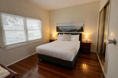 a bedroom with a large bed and two windows at The Original Bel-Air Motel in Port Macquarie