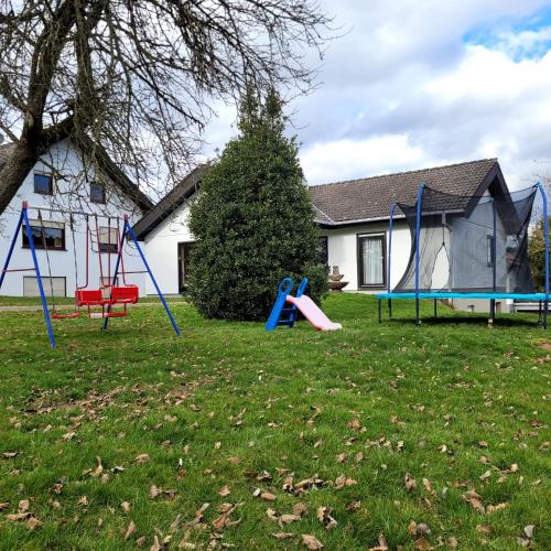 a yard with playground equipment in front of a house at Familiennest-Eifel in Blankenheim