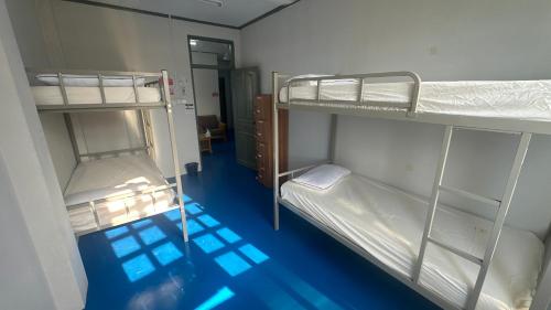 two bunk beds in a room with a blue floor at First Avenue Male Hostel BSB in Bandar Seri Begawan