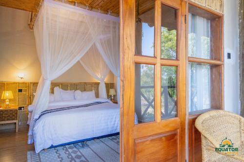 a bedroom with a canopy bed and a window at Equator Lodge & Campsite in Kikorongo