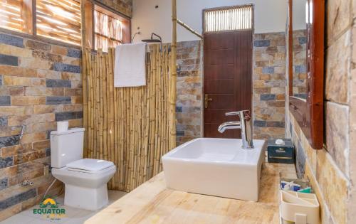 a bathroom with a white toilet and a sink at Equator Lodge & Campsite in Kikorongo