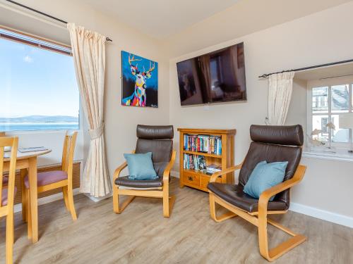 a living room with a table and chairs and a television at Harbour View in Cromarty