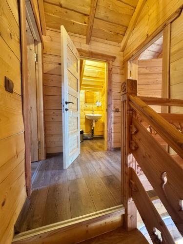 a hallway in a log cabin with a door and a sink at magiy cotteg in Rozhanka Nizhnyaya