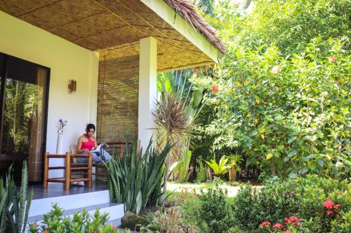 a woman sitting on a chair on the porch of a house at Happy Coconut Camiguin in Mambajao
