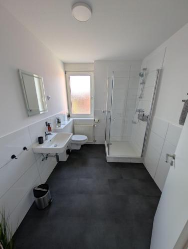 a white bathroom with a sink and a shower at Ferienwohnung Gästehaus Bauer 1 in Heiligenhaus
