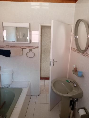 a bathroom with a sink and a toilet and a mirror at Nkotsha The Palace in Diepkloof