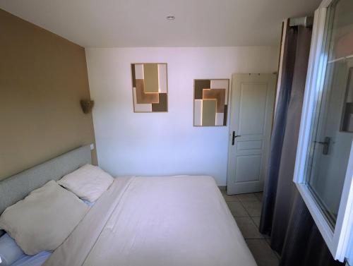 a bedroom with a bed and two pictures on the wall at charmante maisonnette avec spa privatif in Zonza