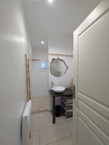 a white bathroom with a sink and a mirror at charmante maisonnette avec spa privatif in Zonza
